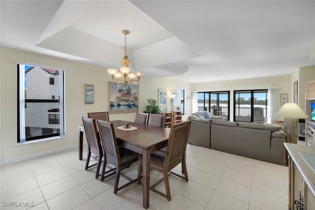 dining area featuring light tile patterned floors, a tray ceiling, and an inviting chandelier