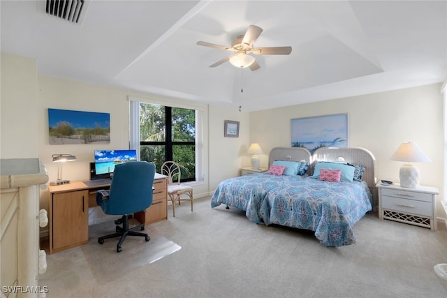 carpeted bedroom featuring a tray ceiling and ceiling fan