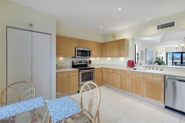 kitchen featuring a chandelier, appliances with stainless steel finishes, light brown cabinets, and sink