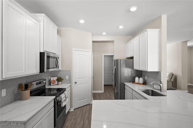 kitchen featuring white cabinets, appliances with stainless steel finishes, light stone countertops, and sink