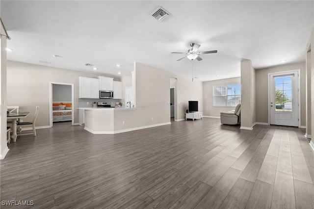 unfurnished living room featuring ceiling fan and dark wood-type flooring