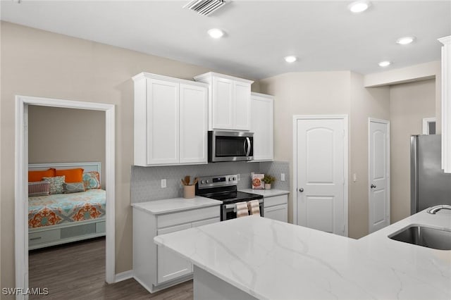 kitchen featuring backsplash, white cabinets, sink, wood-type flooring, and stainless steel appliances