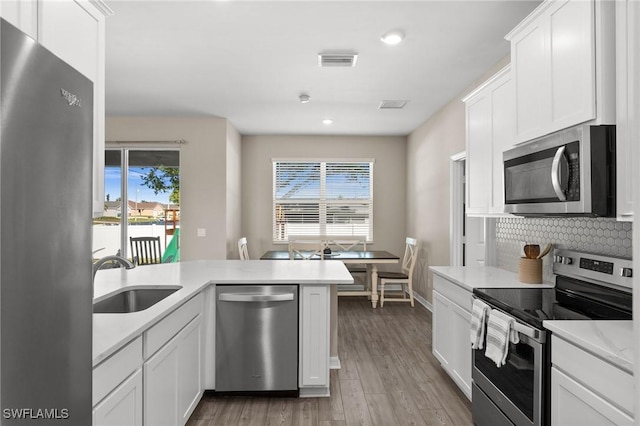 kitchen with white cabinets, appliances with stainless steel finishes, light wood-type flooring, and sink