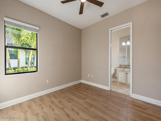 unfurnished bedroom with ensuite bathroom, light wood-type flooring, and ceiling fan