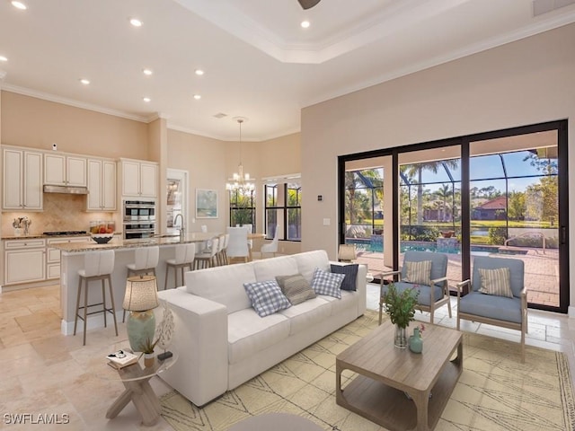 living room featuring a high ceiling, an inviting chandelier, and crown molding