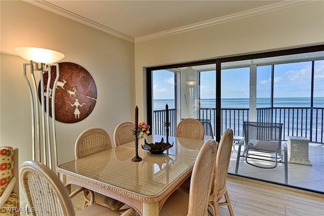 dining room with light wood-type flooring, a water view, and crown molding