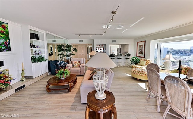 living room featuring light hardwood / wood-style flooring, crown molding, and rail lighting