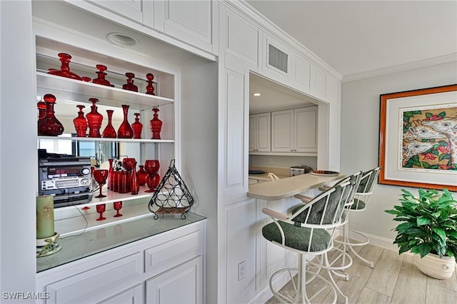 kitchen with light hardwood / wood-style floors, crown molding, and white cabinetry