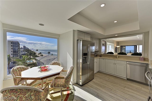 kitchen with stainless steel appliances, a raised ceiling, sink, and gray cabinetry