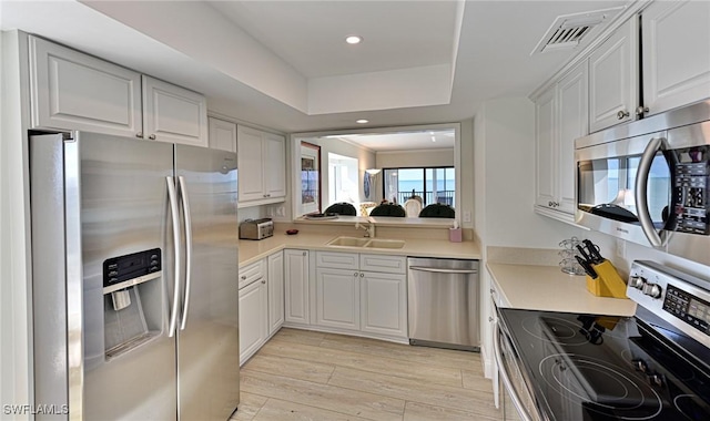 kitchen with sink, white cabinetry, light wood-type flooring, and appliances with stainless steel finishes