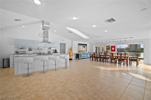 319 Pirates Bight, Naples, FL 34103 - kitchen featuring a kitchen bar, lofted ceiling with skylight, wall chimney exhaust hood, and visible vents