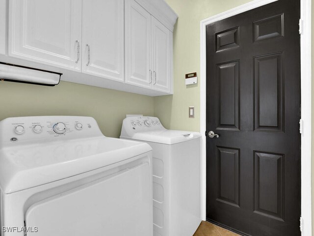 washroom with cabinets, washing machine and clothes dryer, and light tile patterned floors