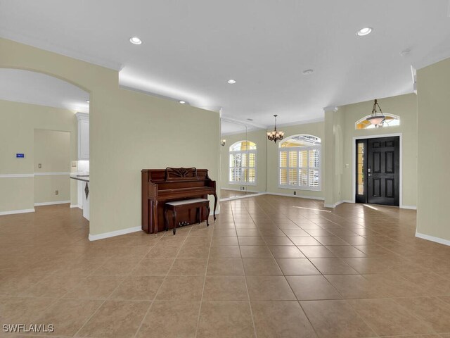 entryway with ornamental molding, a chandelier, and light tile patterned floors