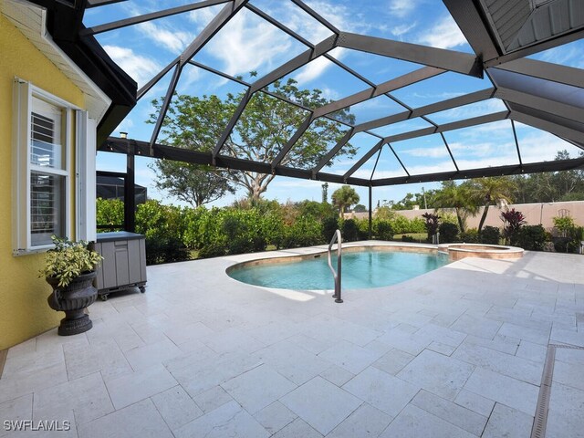 view of pool with a patio, glass enclosure, and an in ground hot tub