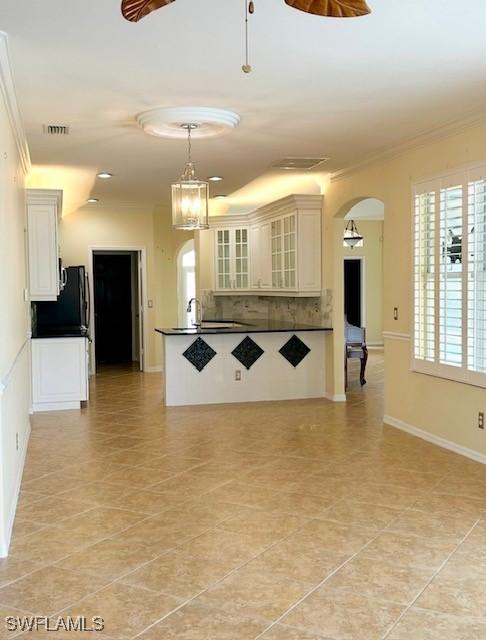 kitchen with white cabinetry, tasteful backsplash, decorative light fixtures, light tile patterned floors, and ornamental molding