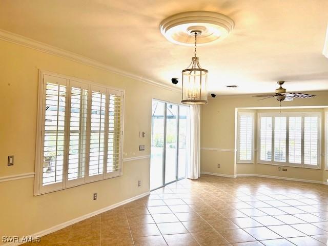 empty room with ceiling fan with notable chandelier, ornamental molding, and light tile patterned flooring