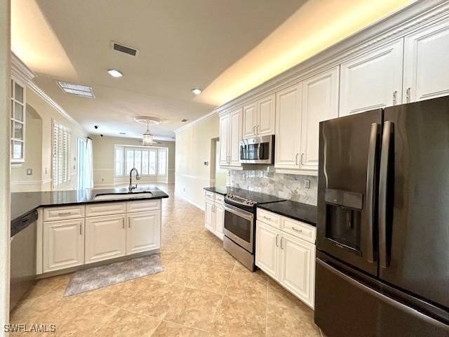 kitchen with white cabinetry, sink, decorative backsplash, stainless steel appliances, and crown molding