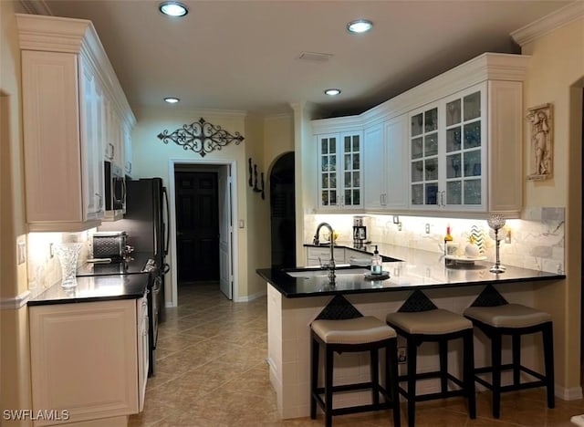 kitchen featuring tasteful backsplash, sink, a breakfast bar area, white cabinets, and kitchen peninsula