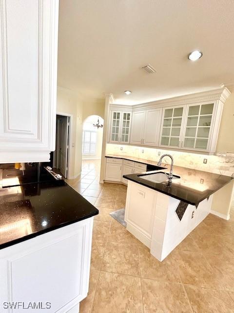 kitchen with white cabinetry, sink, light tile patterned floors, and kitchen peninsula