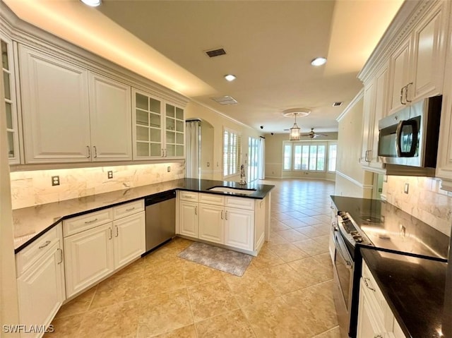 kitchen featuring sink, appliances with stainless steel finishes, backsplash, white cabinets, and kitchen peninsula