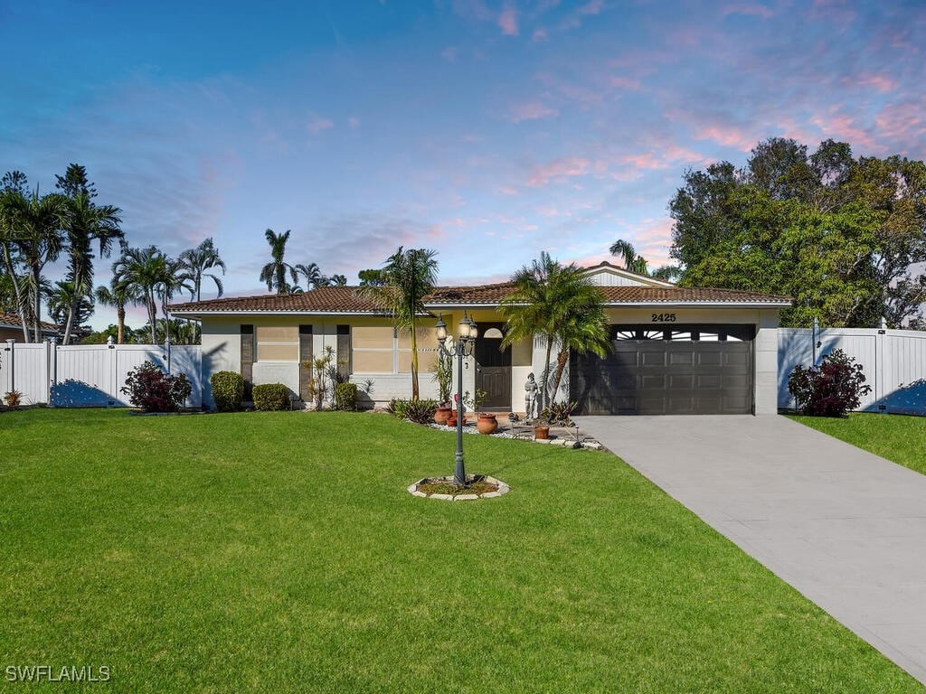 ranch-style house featuring a garage and a yard