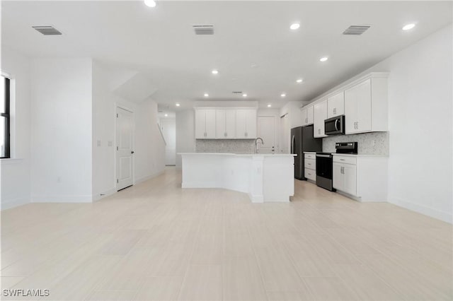 kitchen featuring tasteful backsplash, electric range oven, fridge, an island with sink, and white cabinets