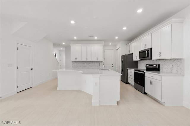 kitchen with sink, appliances with stainless steel finishes, backsplash, an island with sink, and white cabinets