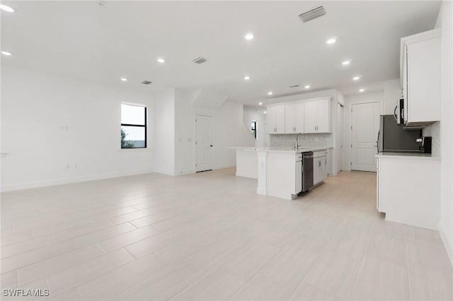 kitchen featuring appliances with stainless steel finishes, white cabinetry, an island with sink, sink, and decorative backsplash