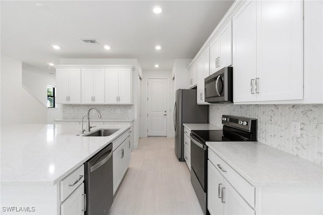 kitchen with stainless steel appliances, sink, decorative backsplash, and white cabinets