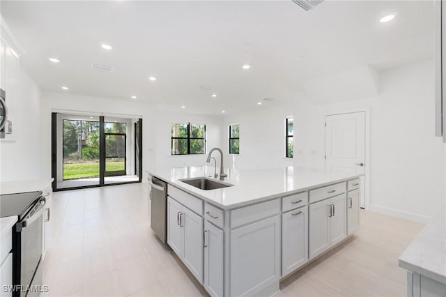 kitchen featuring stainless steel appliances, sink, white cabinets, and a kitchen island with sink