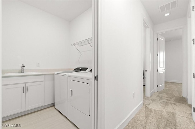 laundry area with cabinets, washing machine and clothes dryer, sink, and light carpet