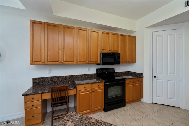 kitchen with light tile patterned flooring, built in desk, dark stone countertops, and black appliances