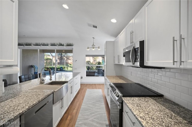 kitchen with white cabinets, light stone counters, and appliances with stainless steel finishes