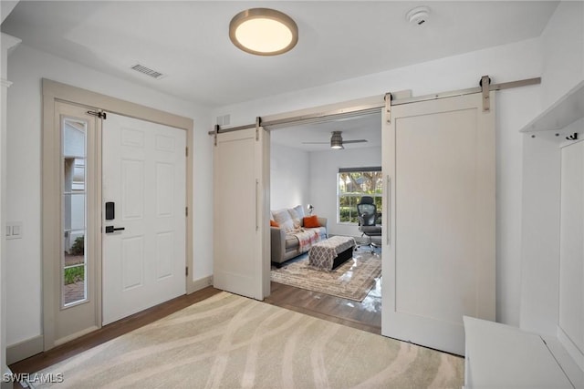 foyer featuring ceiling fan, a barn door, and wood-type flooring