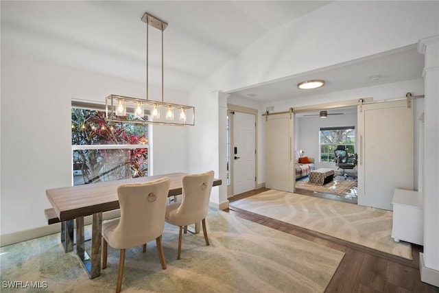 dining area featuring a barn door and vaulted ceiling