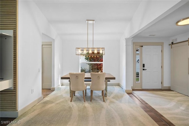 carpeted dining room with a barn door