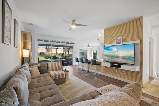 living room with wood-type flooring, ceiling fan with notable chandelier, and sink