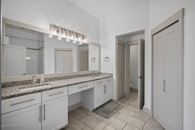 bathroom featuring tiled shower, vanity, toilet, and tile patterned flooring