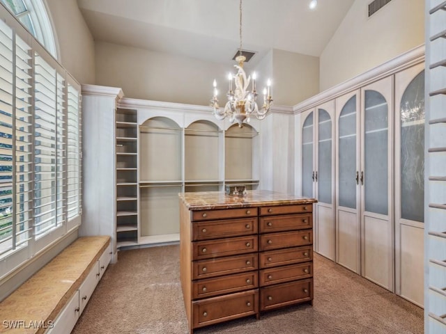 walk in closet with light colored carpet, high vaulted ceiling, and a notable chandelier