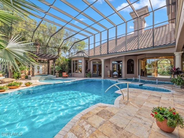 view of pool with glass enclosure, an in ground hot tub, a patio area, and pool water feature