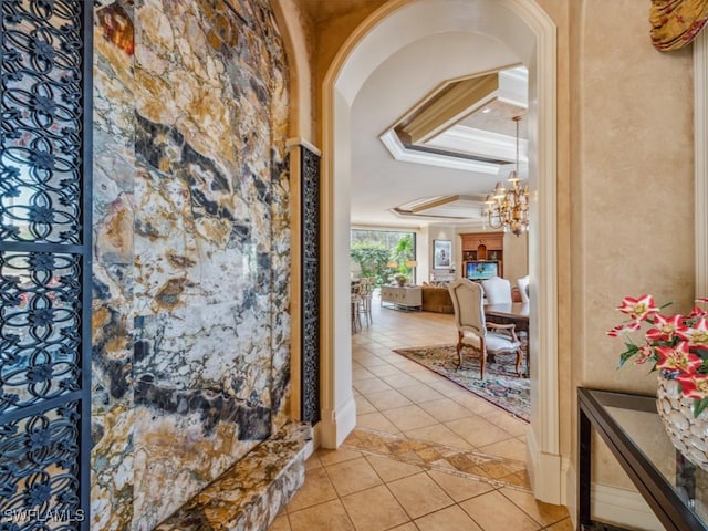 tiled foyer featuring a notable chandelier and crown molding