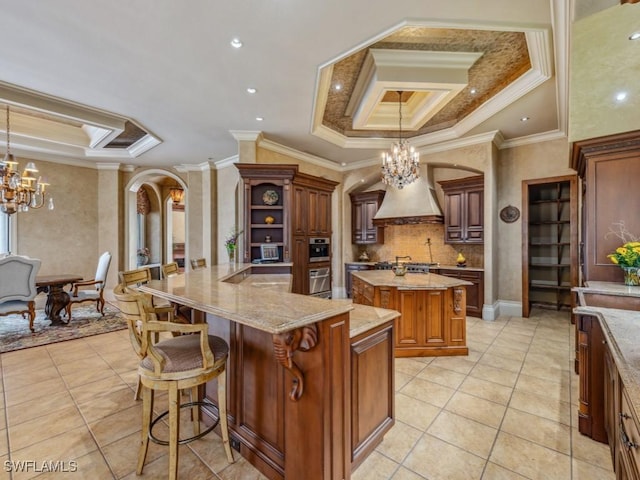 kitchen featuring custom range hood, a tray ceiling, crown molding, and a large island