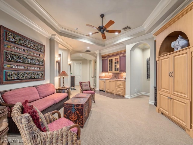 living room with a tray ceiling, ceiling fan, light colored carpet, and ornamental molding