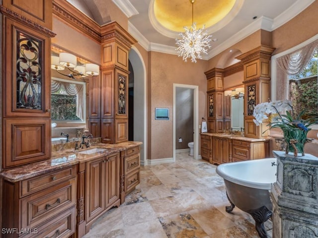 bathroom with ornamental molding, vanity, a tray ceiling, a bath, and toilet