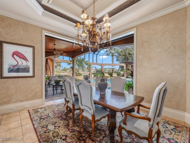 tiled dining space with ceiling fan with notable chandelier, a tray ceiling, and ornamental molding