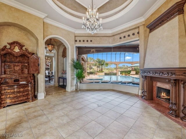 interior space with a raised ceiling, a notable chandelier, crown molding, a towering ceiling, and a fireplace