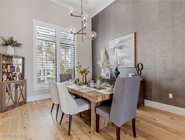 dining space with a chandelier, light wood-type flooring, and crown molding