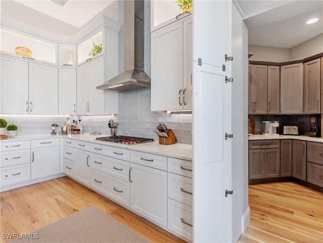 kitchen featuring stainless steel gas stovetop, white cabinetry, and wall chimney exhaust hood