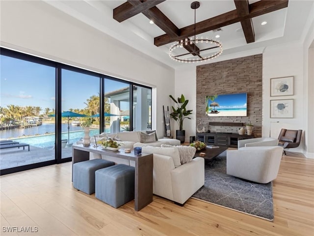 living room with coffered ceiling, light wood-type flooring, a water view, beamed ceiling, and a notable chandelier