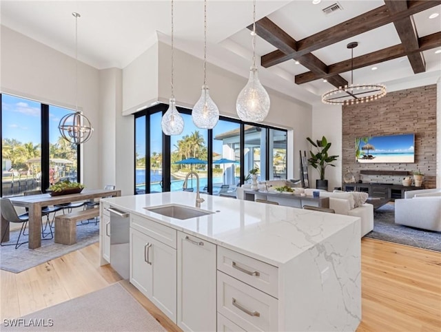 kitchen featuring sink, a center island with sink, white cabinetry, and light hardwood / wood-style floors